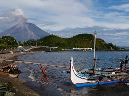 Pescadores trabajan en las inmediaciones del volcán, que emite una larga columna de humo. AP/B. Marquez