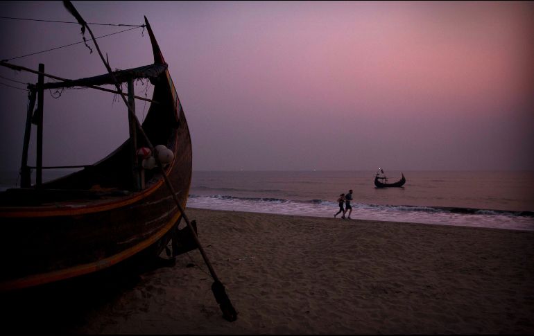 Botes de pescadores se ven anclados en Cox's Bazar, Bangladesh, mientras personas corren por la playa. AP/M. Swarup