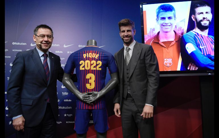 El defensa Gerard Pique posa junto al presidente del Barcelona, Josep Maria Bartomeu, en el anuncio oficial de la renovación de su contrato con el equipo realizado en el Camp Nou de Barcelona. AFP/L. Gene