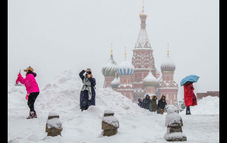 Turistas toman fotos frente a la catedral de San Basilio, en Moscú, en una plaza Roja cubierta de nieve. AFP/M. Antonov