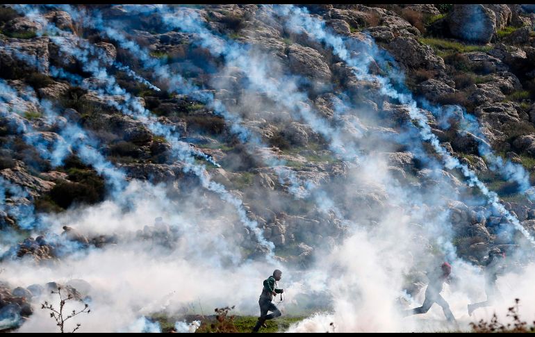 Palestinos huyen del gas lacrimógeno en enfrentamientos con soldados israelíes en Mugheer, Cisjordania. AFP/A. Momani