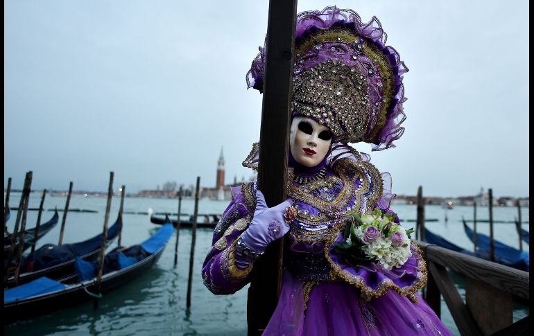 Un juerguista enmascarado posa con traje de carnaval tradicional posa en la Plaza de San Marcos, Venecia. AFP / T. Fabi