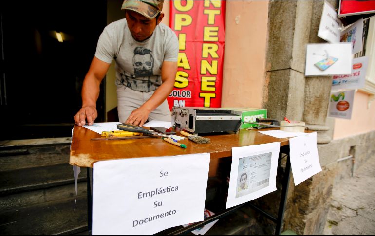 Un hombre plastifica un documento de un ciudadano que acudió a votar. EFE/J. Jácome