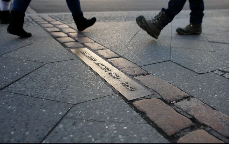 Varias personas caminan sobre los adoquines que marcan la antigua división del Muro de Berlín. EFE / A. Becher