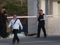 Un transeúnte camina a la entrada del asentamiento de Karmei Tzur, vigilada por fuerzas de seguridad tras el incidente violento. AFP/H. Bader