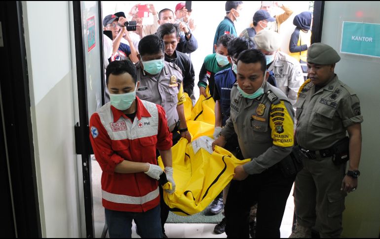 Rescatistas y policías trasladan el cuerpo de una de las víctimas de un choque de autobús a un hospital en Tangerang, Indonesia. El accidente de ayer en la isla de Java dejó al menos 27 muertos. AFP/D. Sanjaya