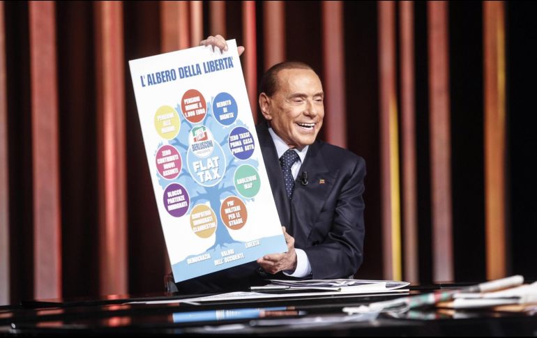 El ex primer ministro italiano Silvio Berlusconi muestra un cartel electoral durante el programa de la televisión italiana 'In mezz'ora piu', en Roma, Italia. EPA /G. Lami