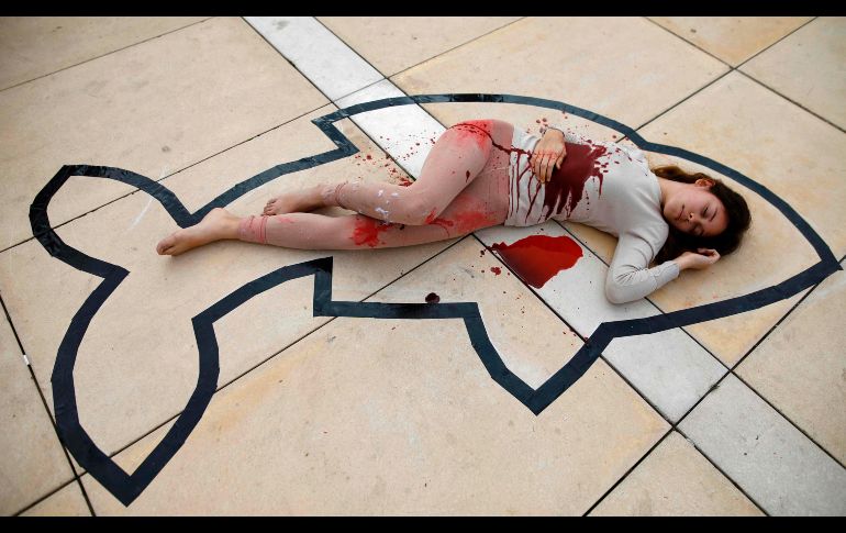 Un activista de Anonymous for Animal Rights con sangre artificial y emulando una escena de crimen participa en una protesta en Tel Aviv, Israel, en contra de la matanza de animales. AFP/M. Kahana