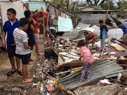 Una familia revisa los estragos que el ciclón causó a su vivienda. AFP/J. Pulu