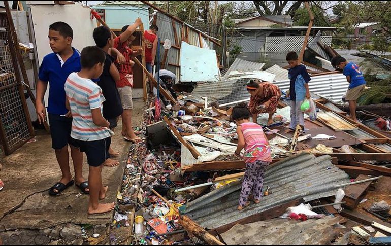 Una familia revisa los estragos que el ciclón causó a su vivienda. AFP/J. Pulu