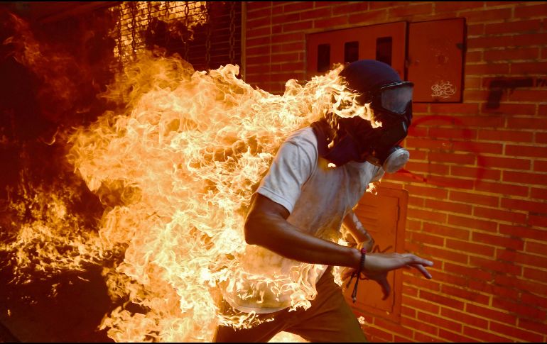 La instantánea recoge el momento en el que José Víctor Salazar, de 28 años, sale corriendo envuelto en llamas al ser alcanzado por un chorro de gasolina. AFP/R. Schemidt