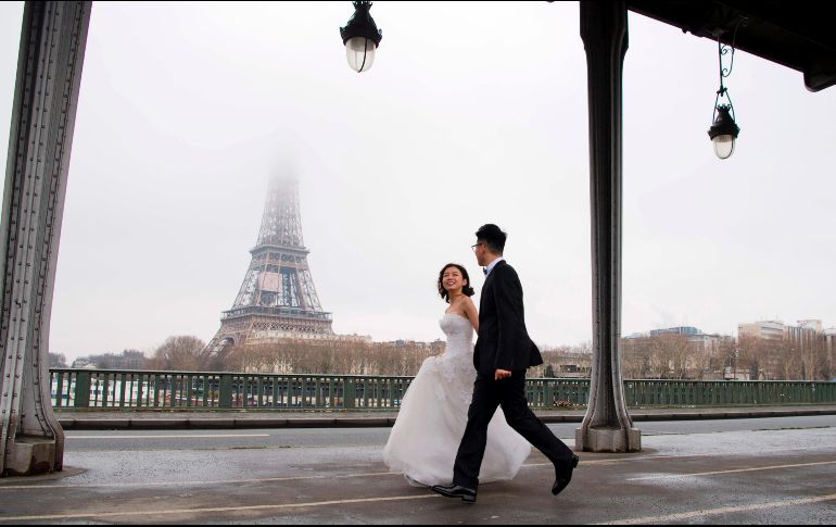 Unos novios caminan en el puente Bir-Hakeim, con la torre Eiffel de fondo, en París. AFP/A. Jocard