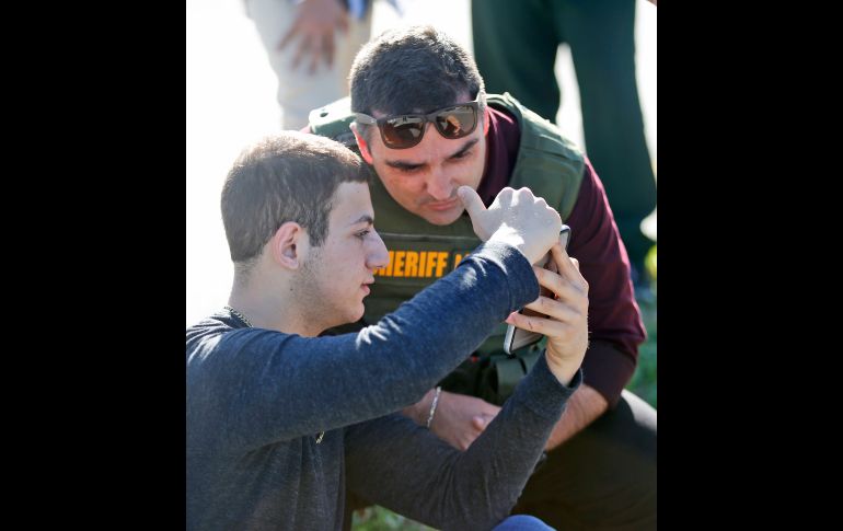 Un estudiante muestra a un policía material de su teléfono.