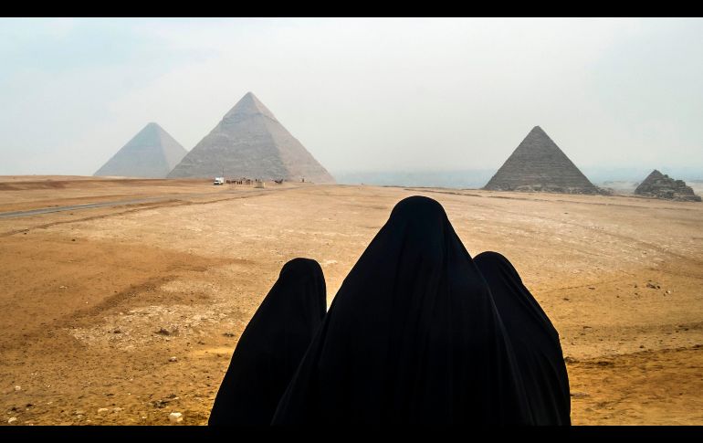 Mujeres con velos observan las pirámides en Giza, Egipto. AFP/K. Desouki