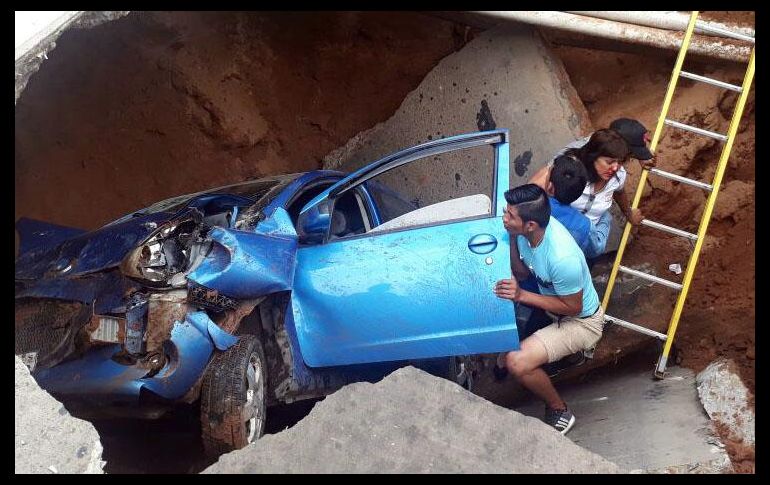 Personas tratan de rescatar a una de las víctimas de un accidente en Santa Cruz, Bolivia. Dos mujeres que se movilizaban en auto se salvaron de morir tras caer hoy en un enorme socavón en una calle, del que fueron rescatadas. EFE/ J. Torrejón