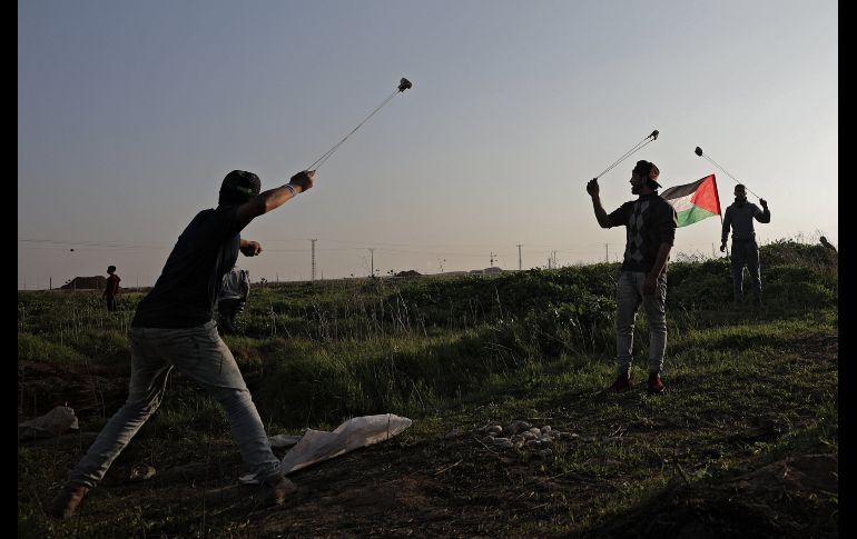 Manifestantes palestinos lanzan piedras durante enfrentamientos con tropas israelíes, cerca de la frontera, en la Franja de Gaza. EFE / M. Saber
