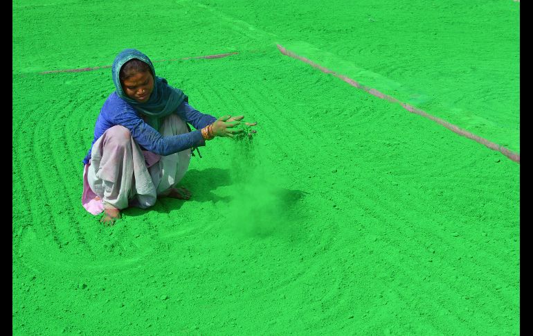 Una mujer india limpia el polvo de color que será utilizado en el Festival Holi que se celebra para recibir la primavera. AFP