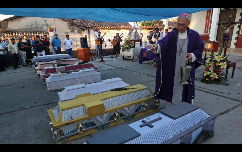 Un sacerdote bendice los ataúdes de las víctimas del accidente. AP/L. Cruz