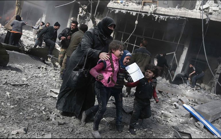 Sirios corren durante un bombardeo del régimen sirio sobre la población de Hamouria, controlada por combatientes rebeldes. AFP/A. Eassa