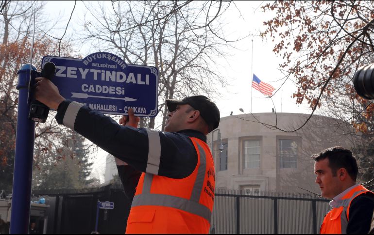 Un trabajador fija un placa con el nuevo nombre de una calle, que se lee 
