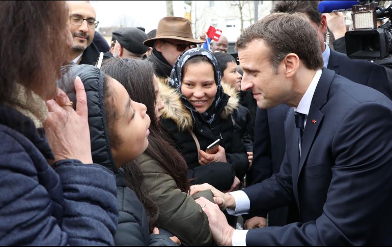 El presidente de Francia, Emannuel Macron, saluda a residentes en una visita a la ciudad francesa de Les Mureaux. AFP/L. Marin