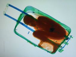 Cuando la maleta pasa por el escáner, los agentes observan la figura humana del menor. AFP /