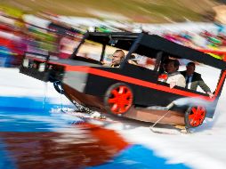 Asistentes se lanzan al agua en su trineo decorado, con el objetivo de deslizarse a lo largo de la piscina de agua excavada en la nieve. EFE / V. Flauraud
