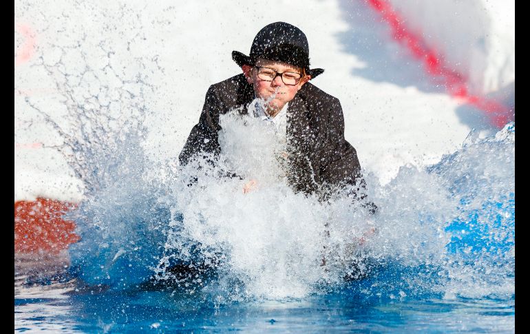 Un joven con sombrero y lentes se estrella en su trineo contra la fría piscina. EFE / V. Flauraud