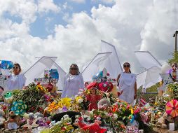 Diecisiete personas vestidas como ángeles se mantuvieron de pie junto al monumento conmemorativo improvisado a las afueras de la escuela. AP/ D. Santiago