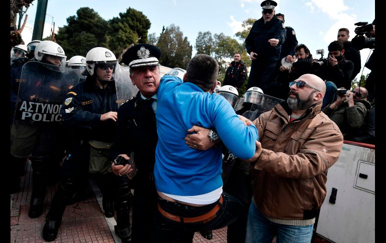 Policías empujan a un hombre en una manifestación en Atenas, Grecia, contra una reforma educativa. AFP/L. Gouliamaki