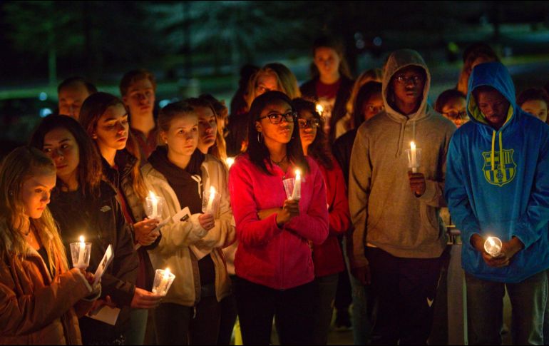 Varios alumnos de la escuela donde ocurrió la masacre encienden velas durante un homenaje a sus compañeros fallecidos. AP/H. Rousseau