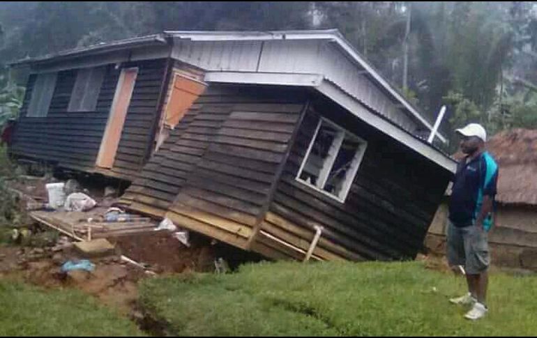 Un hombre se para junto a su casa colapsado por un sismo en Halagoli, Papúa Nueva Guinea. Los graves daños en las redes telefónicas y los caminos que causó un terremoto  están obstaculizando los esfuerzos gubernamentales por evaluar la destrucción. AP/J. Wepii