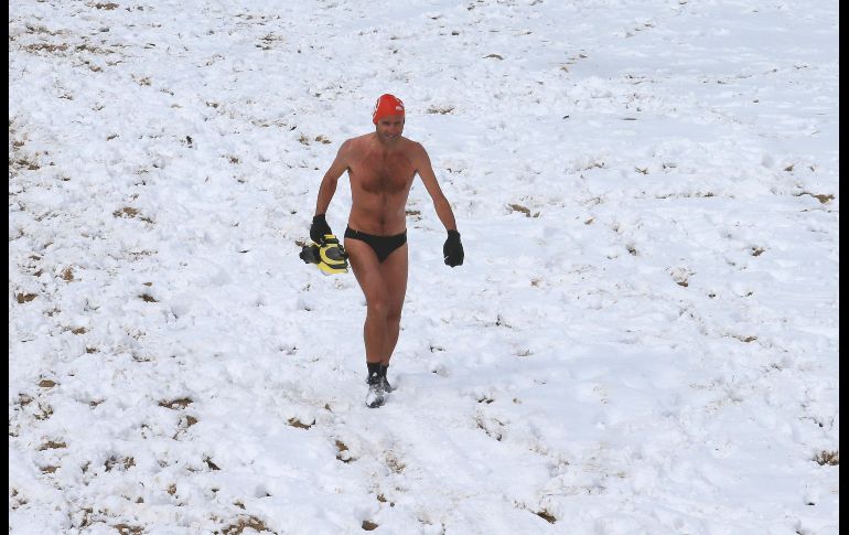 Un hombre camina sobre la playa nevada de Biarritz, en Francia, tras aventurarse y bañarse en aguas del océano Atlántico mientras se registran temperaturas congelantes. AP/B. Edme