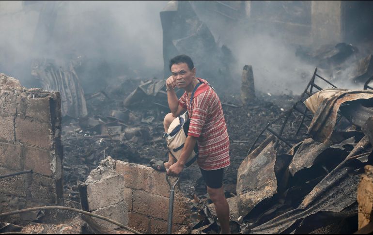 Un habitante regresa a viviendas quemadas para recuperar sus pertenencias, tras un incendio en Quezon City, Filipinas. EFE/R. Dela Pena
