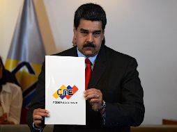 Maduro muestra el documento del acuerdo luego de la firma entre él y los candidatos opositores. AFP / F. Parra