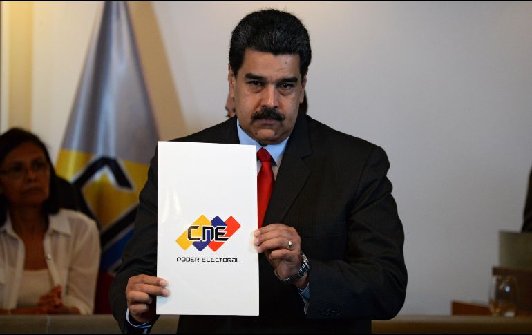 Maduro muestra el documento del acuerdo luego de la firma entre él y los candidatos opositores. AFP / F. Parra