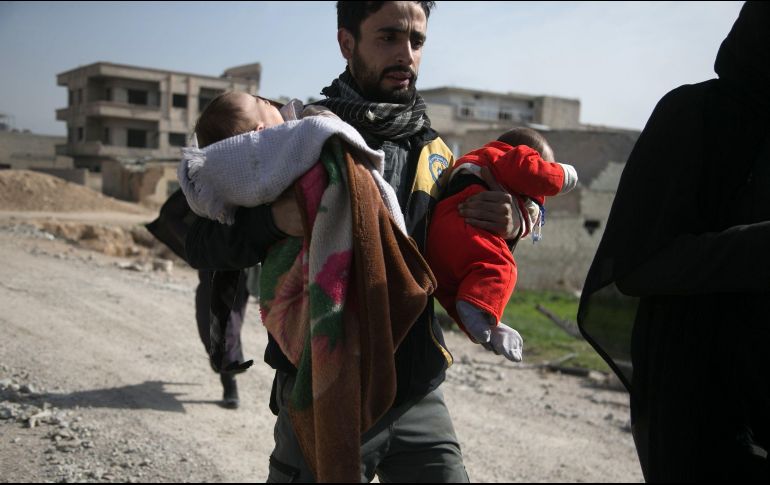 Un voluntario de la defensa civil siria carga a dos niños mientras ayuda a evacuarlos de sus casas en Hamouria, tras ataques aéreos contra los rebeldes. El gobierno sirio retomó el control de una parte de la región de Gouta Oriental. AFP/B. Eassa