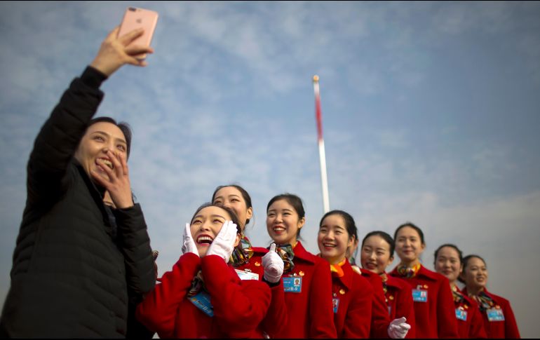 Edecanes reaccionan tras tomarse una foto durante la apertura del plenario de la Asamblea Nacional Popular de China, que inicia hoy en Pekín, China. AP/M. Schiefelbein