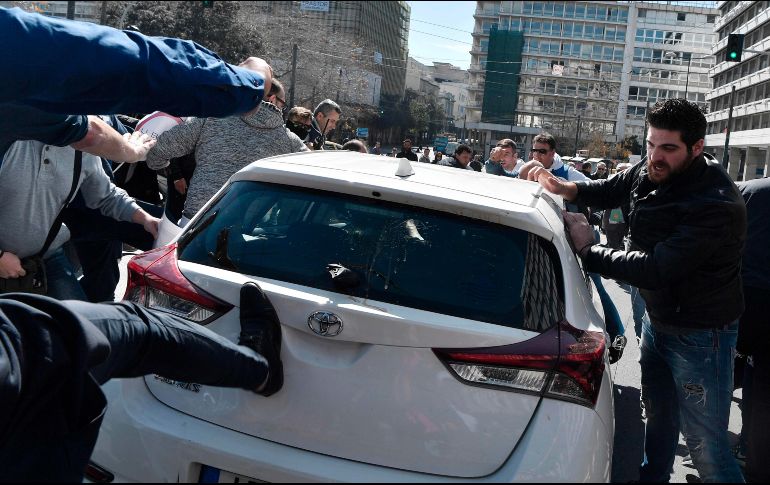 Choferes de taxi atacan un vehículo de un conductor de Uber durante una protesta en Atenas, Grecia, en contra de una legislación sobre el servicio a través de la aplicación. AFP/L. Gouliamaki
