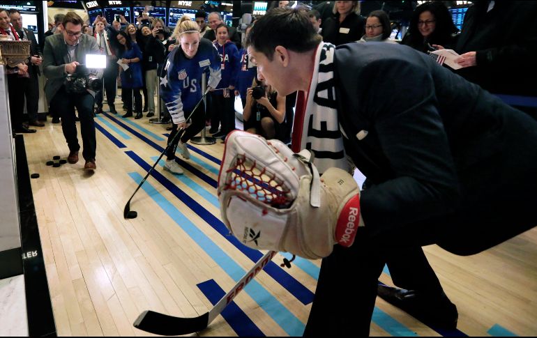 Jocelyne Lamoureux-Davidson, del equipo de hockey estadounidense ganador del oro olímpico, lanza un disco a Tom Farley, presidente de la Bolsa de Valores neoyorquina, previo a dar el campanazo de apertura de la Bolsa en Nueva York. AP/R. Drew