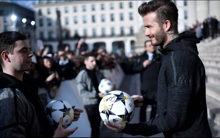 El ex astro del futbol David Beckham firma un balón afuera del palacio Brongniart en París, en el marco de un evento de Adidas. AFP/S. De Sakutin