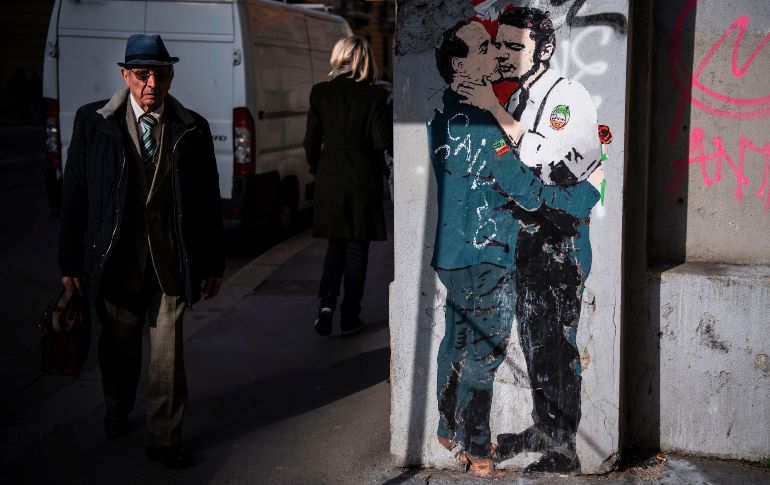 Un hombre pasa junto a un mural del artista TVBoy en Milán, Italia, que muestra un beso entre Silvio Berlusconi (i), líder del partido Forza Italia, y Matteo Renzi, líder del Partido Democrático. AFP/M. Bertorello