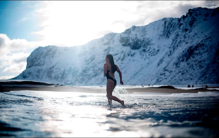 Una mujer se mete al mar en Unstad, Noruega, localizada en el círculo polar ártico y donde se registran temperaturas de -5 grados centígrados. AFP/O. Morin