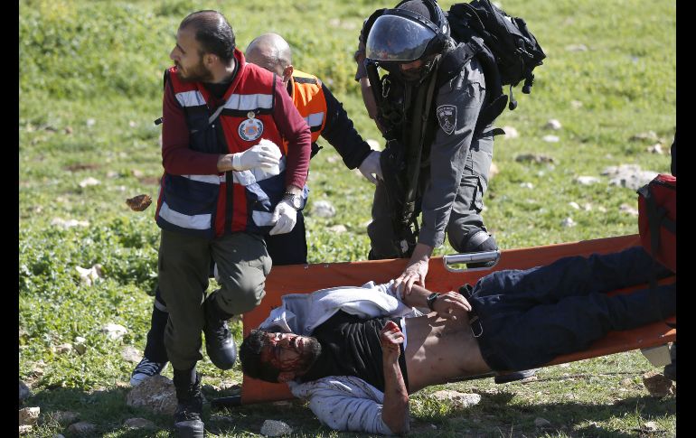 Un soldado israelí intenta detener a un manifestante palestino herido, mientras lo trasladan voluntarios de la defensa civil palestina en Birzeit, Cisjordania. AFP/A. Moman
