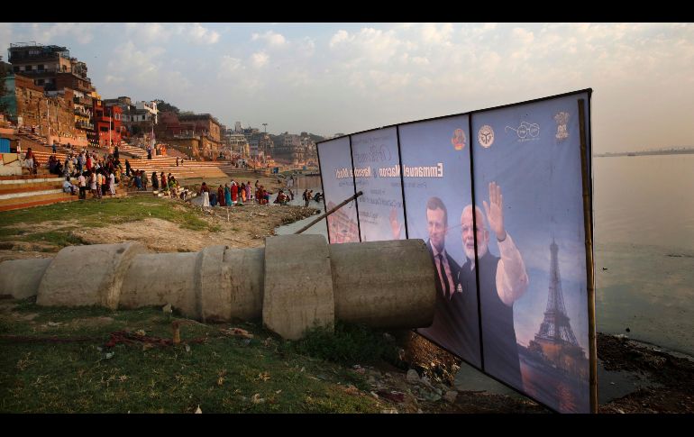 Un póster de bienvenida al presidente francés Emmanuel Macron y el primer ministro indio Narendra Modi se ve colocado frente a una pipa del drenaje hacia el río Ganges en Varanasi. Macron y Modi visitarán hoy esta ciudad india. AP/R. Kumar Singh