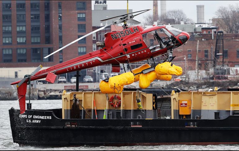 Una grúa levanta un helicóptero que se estrelló anoche en el río Este de Nueva York. Al menos cinco personas murieron en el accidente. AP/M. Lennihan