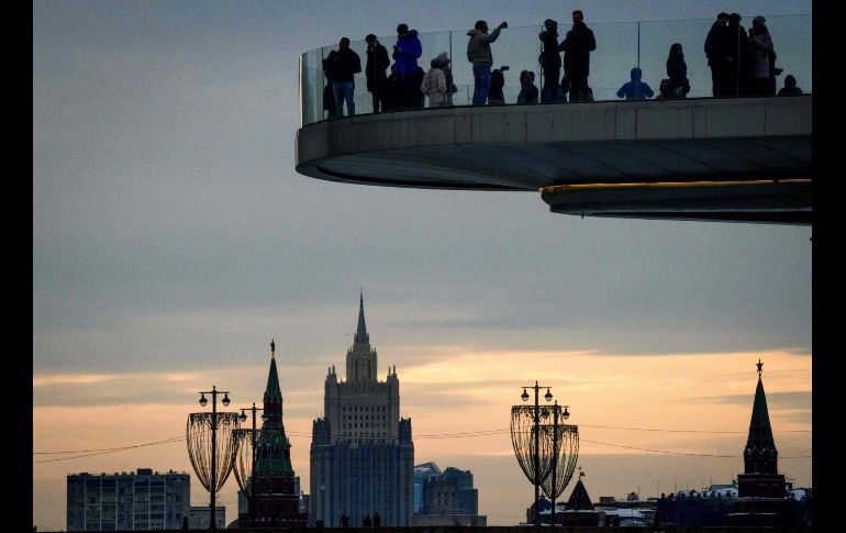 Personas observan desde un puente peatonal en el parque Zaryadye, con las torres del Kremlin y las oficinas del Ministerio del Exterior ruso al fondo, en Moscú. AFP/M. Antonov