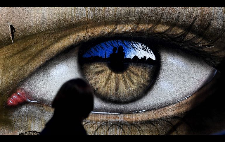 Una niña pasa junto a un ojo, obra del artista británico My Dog Sighs, en Roma. AFP/T. Fabi
