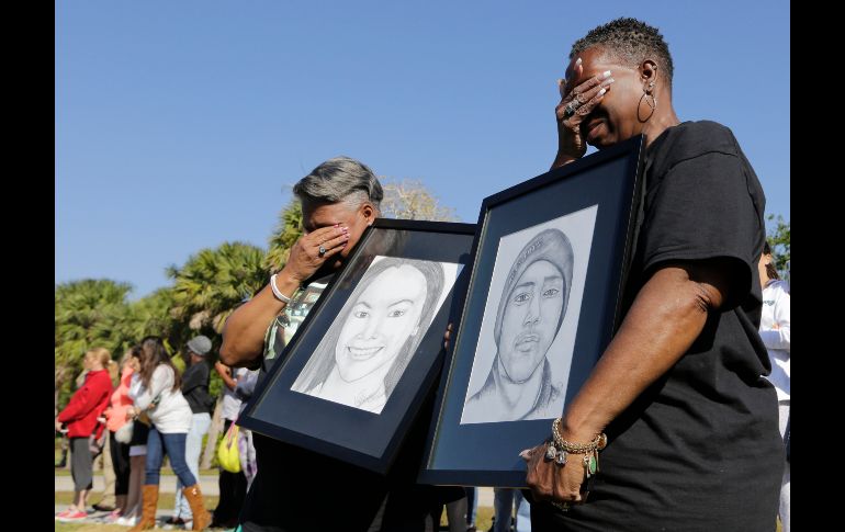 Mujeres afuera de la escuela en Parkland, Florida, sostienen dibujos de Meadow Pollacks y Joaquin Oliver, fallecidos en el tiroteo.