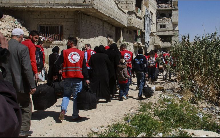 Trabajadores de la Media Luna Roja ayudan en la evacuación de un nuevo grupo de civiles de Guta Oriental a través de un corredor seguro a campamentos de refugiados en la zona rural de Damasco. EFE/SANA